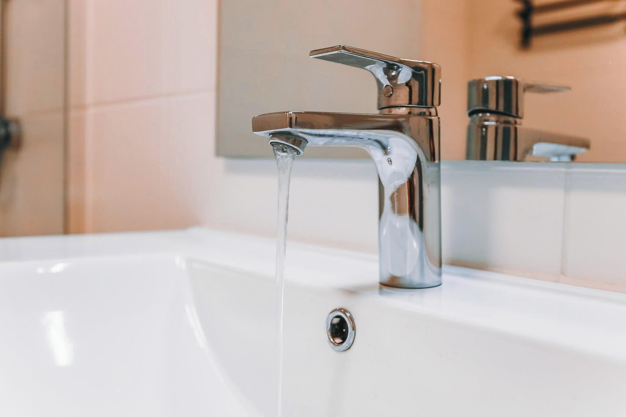 A bathroom sink with a chrome faucet and running water.