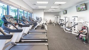 Un gimnasio con cintas de correr, máquinas de pesas y pelotas de ejercicio.