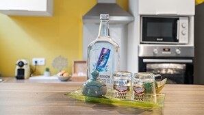 A kitchen with a microwave, oven, and a bottle of alcohol on the counter. - Golden Oasis - One Bedroom Apartment, Sleeps 2 (Le Marin)