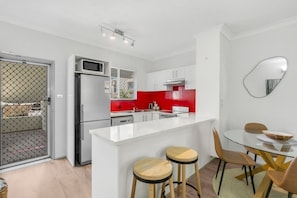 Una cucina moderna con isola bianca, zoccolo rosso e elettrodomestici in acciaio inossidabile.