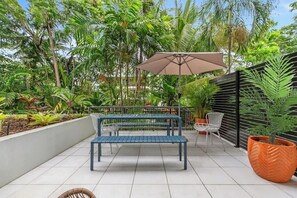 Un patio con una panchina, sedie e un ombrellone grande.