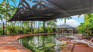 A swimming pool with a sunshade, lounge chairs, and tropical vegetation. - Leafy Solace—A Contemporary Cairns City Hideaway (Cairns)