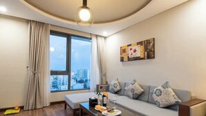Ein modernes Wohnzimmer mit einer Couch, einem Couchtisch, einem Esstisch und einem großen Fenster mit Vorhängen.