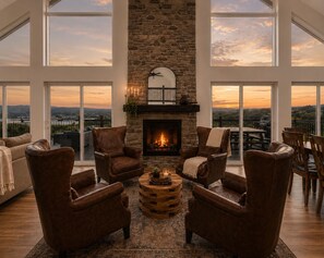 A spacious living room with leather armchairs, a central coffee table, and a stone fireplace.