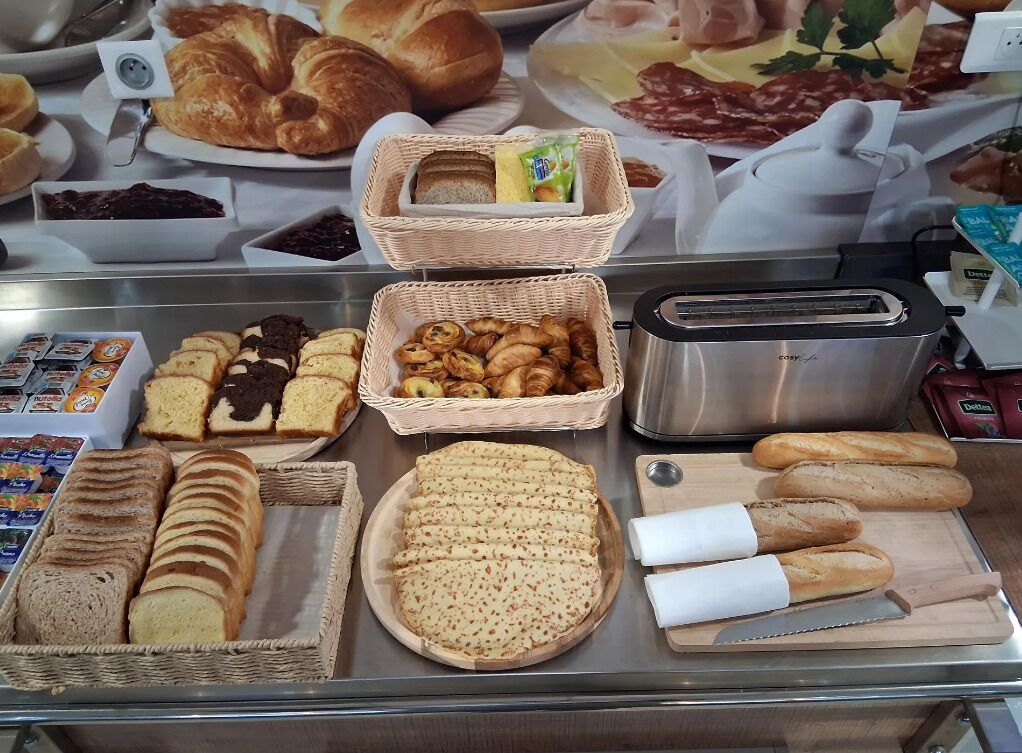 A breakfast buffet with various breads, pastries, and spreads.