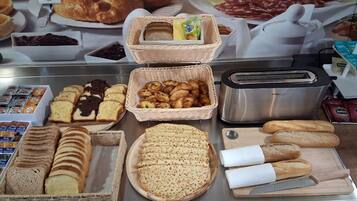 A breakfast buffet with various breads, pastries, and spreads.