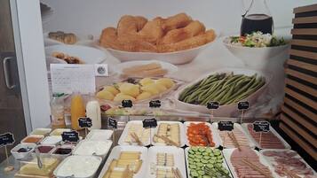 Ein reichhaltiges Buffet mit verschiedenen Speisen, darunter Brot, Obst, Gemüse und Fleisch.
