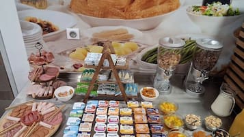 A buffet table with various food items including meats, cheeses, fruits, and dairy products.