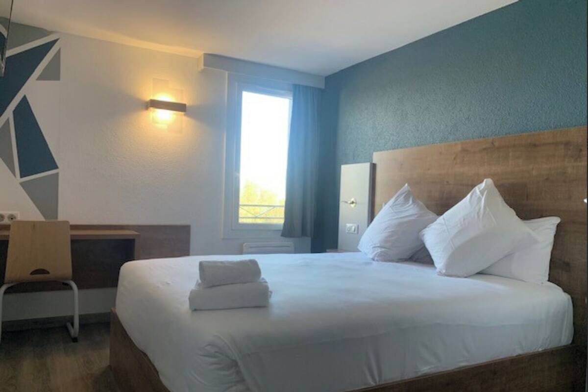 Una habitación de hotel con una cama grande, un escritorio y una ventana con cortinas.