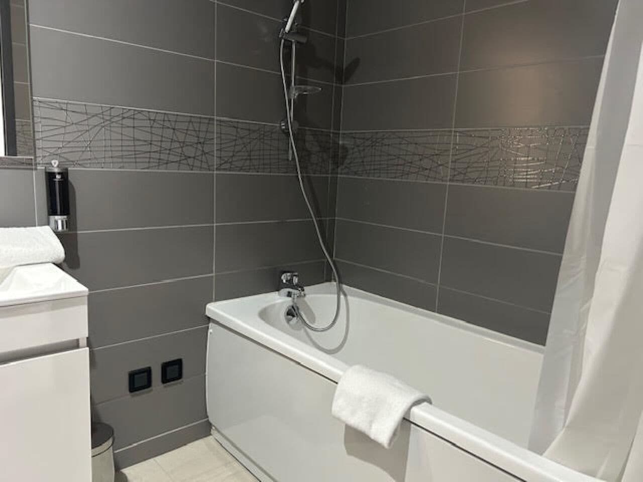 Une salle de bain moderne équipée d’une baignoire, d’une douche et d’un porte-serviettes.