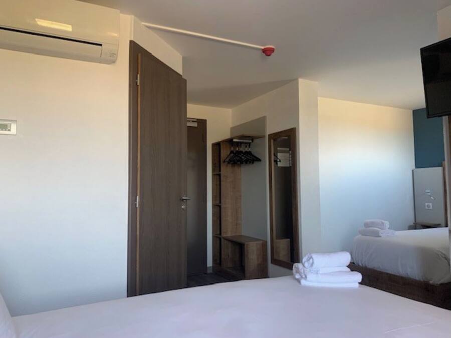 A hotel room with a bed, a wardrobe, a mirror, and a television.