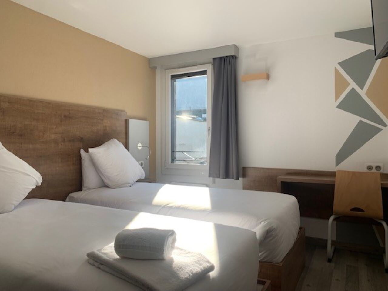 Et hotelværelse med to senge, et skrivebord og havudsigt.