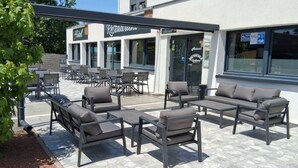 An outdoor seating area with modern furniture, a restaurant sign, and a building facade.