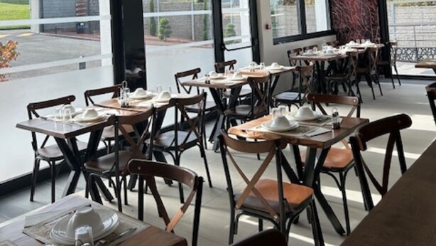 A modern dining area with tables and chairs, large windows, and a ceiling with geometric patterns.
