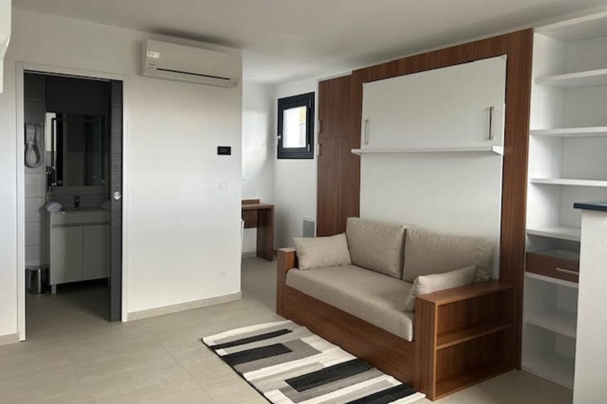 Una sala de estar moderna con un sofá, un aparador de madera y una estantería empotrada.