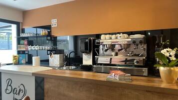 A modern bar area with a coffee machine, shelves with cups and condiments, and a sign that reads "Bar".