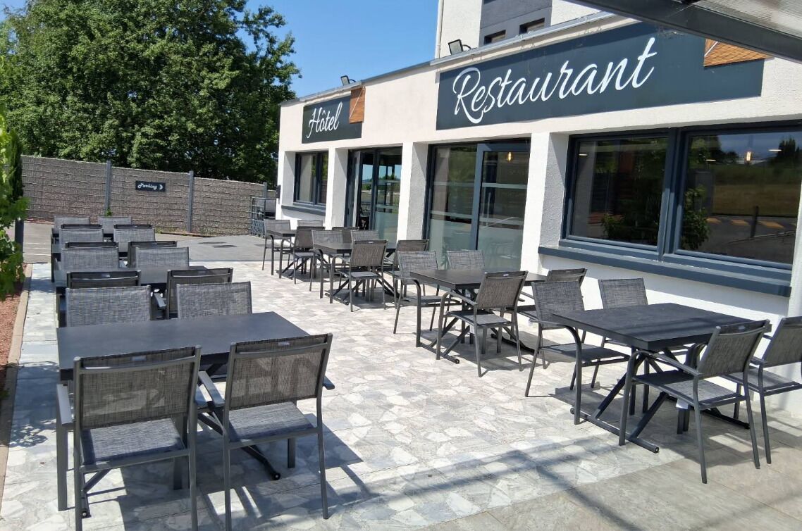 An outdoor patio area with multiple tables and chairs, a sign for a restaurant, and a hotel sign.