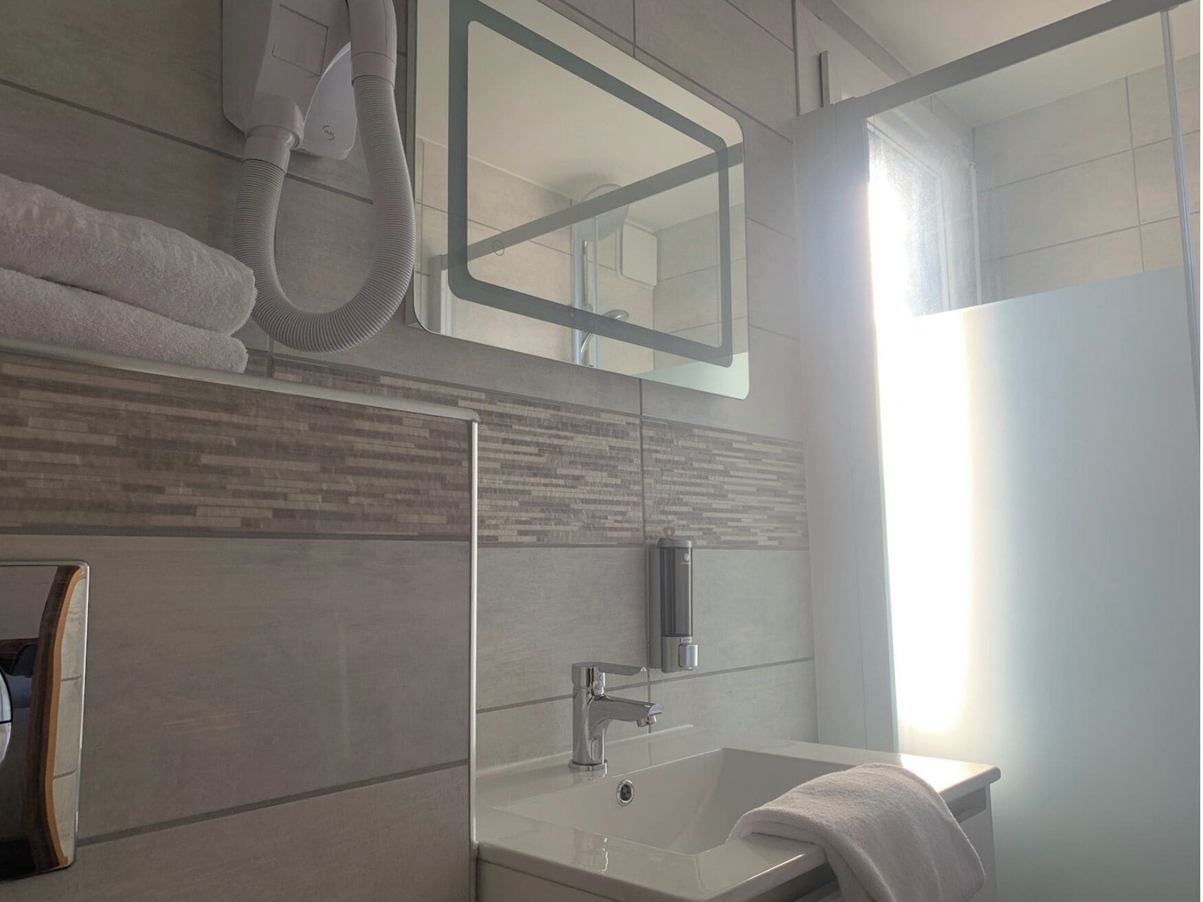 Un baño moderno con un espejo grande, un lavabo y un perchero para toallas.