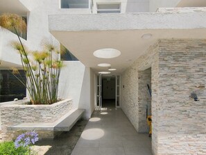 A modern building with a stone facade, a narrow pathway, and a planter with plants. - Oceana Suites Distrito Verde (La Serena)