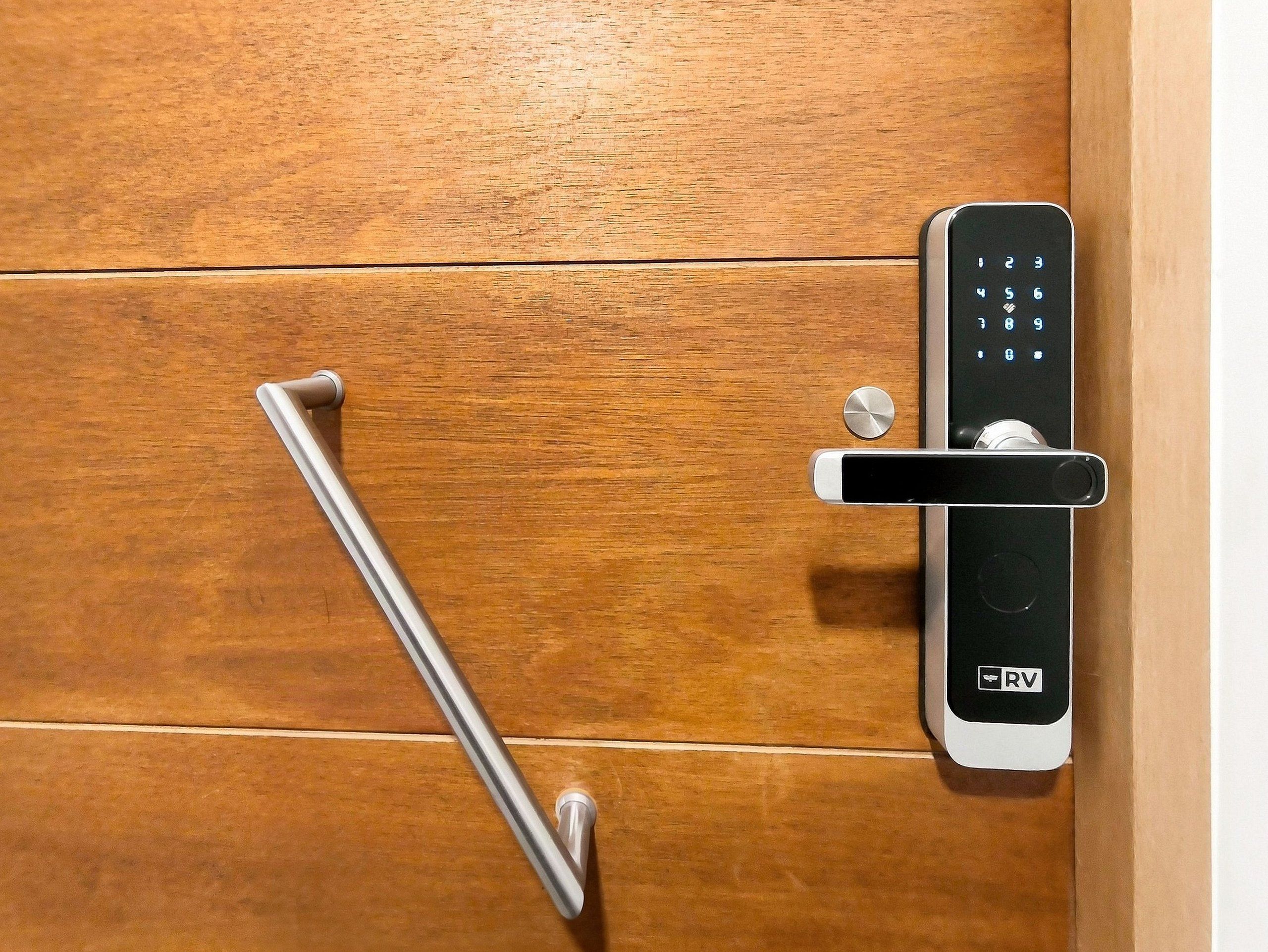 Una puerta moderna con cerradura electrónica de teclado numérico y un picaporte metálico.