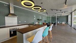 A modern kitchen with a central island, bar stools, and pendant lighting. - Oceana Suites Distrito Verde (La Serena)