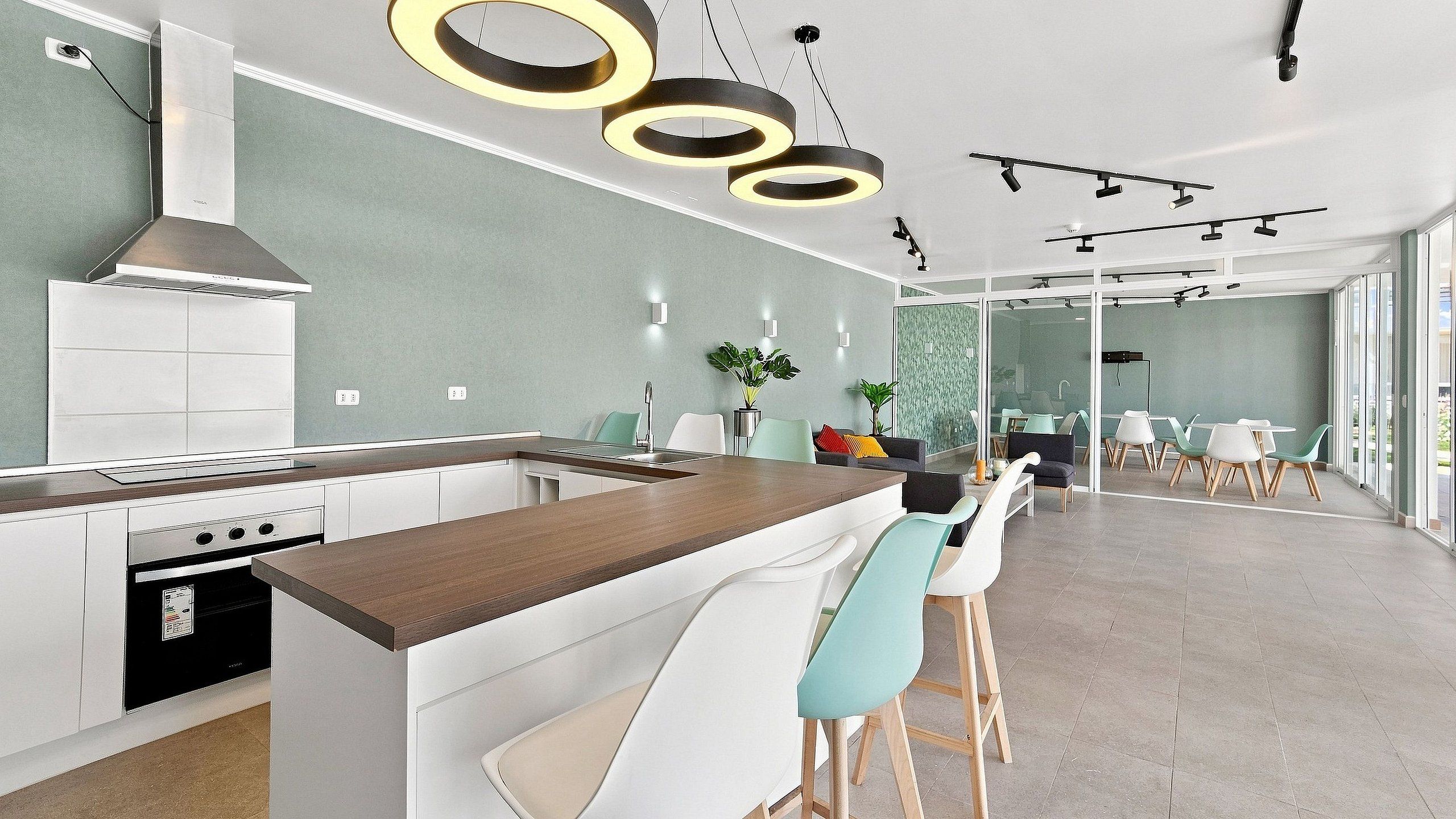 Una cocina moderna con una isla central, taburetes de bar y un comedor con sillas y una mesa.