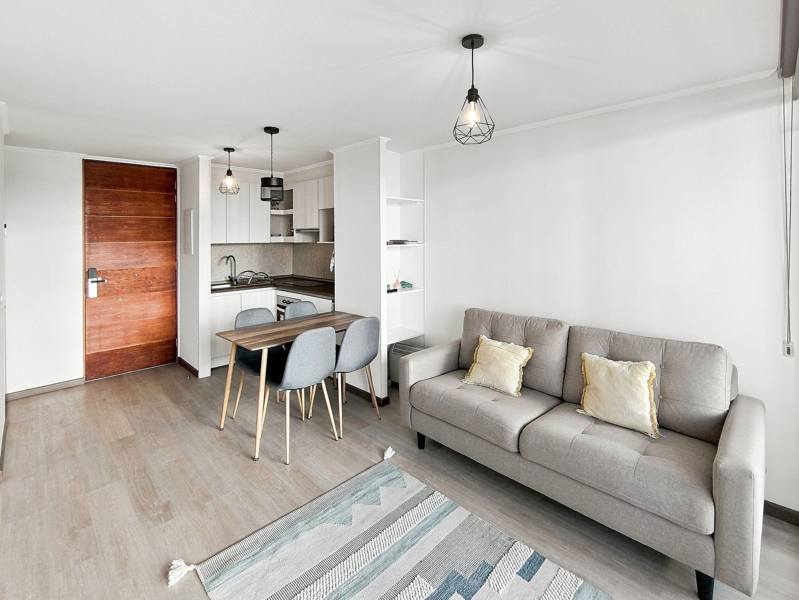 A modern living space with a dining area, sofa, and kitchen.