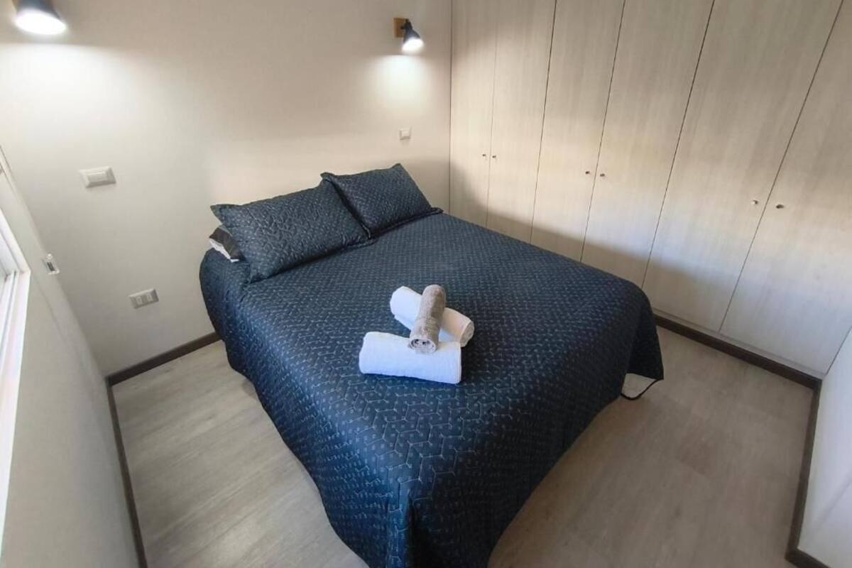 A bedroom with a bed, pillows, a towel, and a wardrobe.