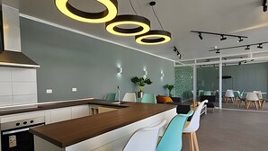 A modern kitchen with a central island, bar stools, and a dining area with chairs and tables. - Oceana Suites Distrito Verde (La Serena)