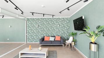 A modern living room with a sofa, coffee table, and a large plant.