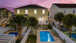 Zona residencial con dos piscinas, un balcón y un patio trasero cercado con palmeras.