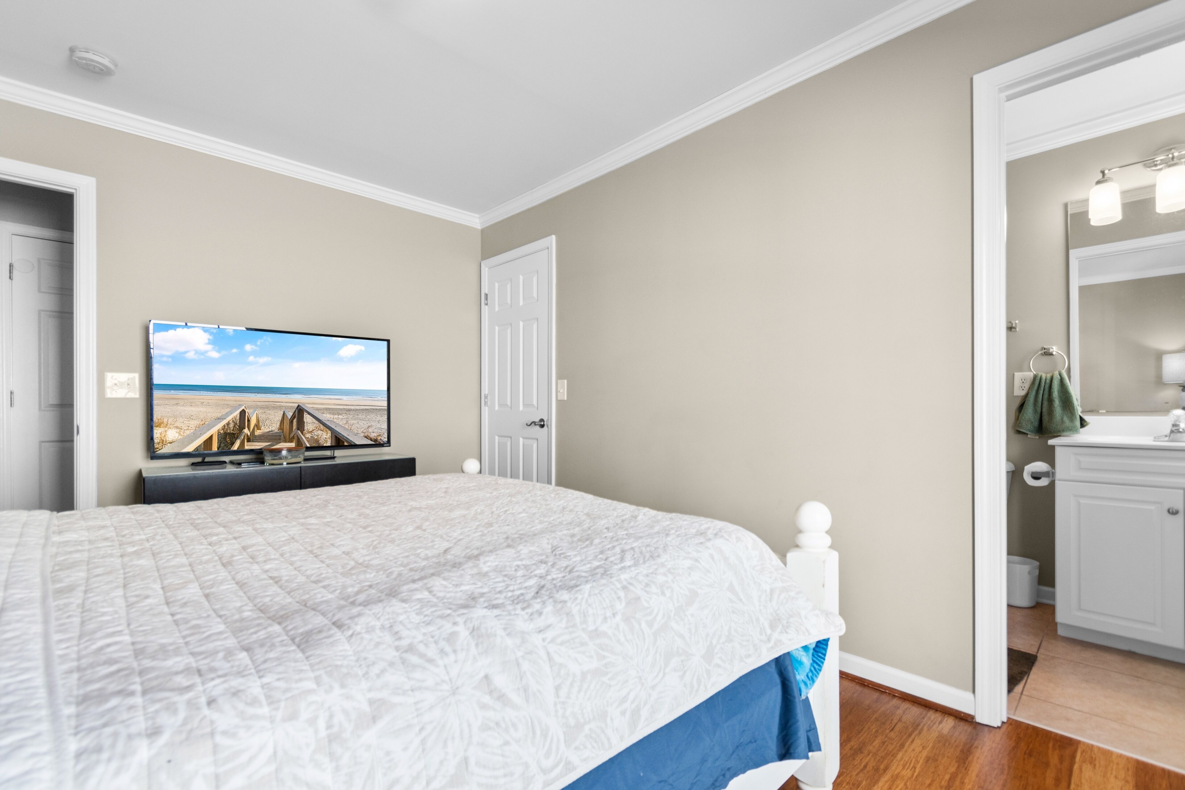 A bedroom with a bed, a television on the wall, and a door leading to a bathroom.