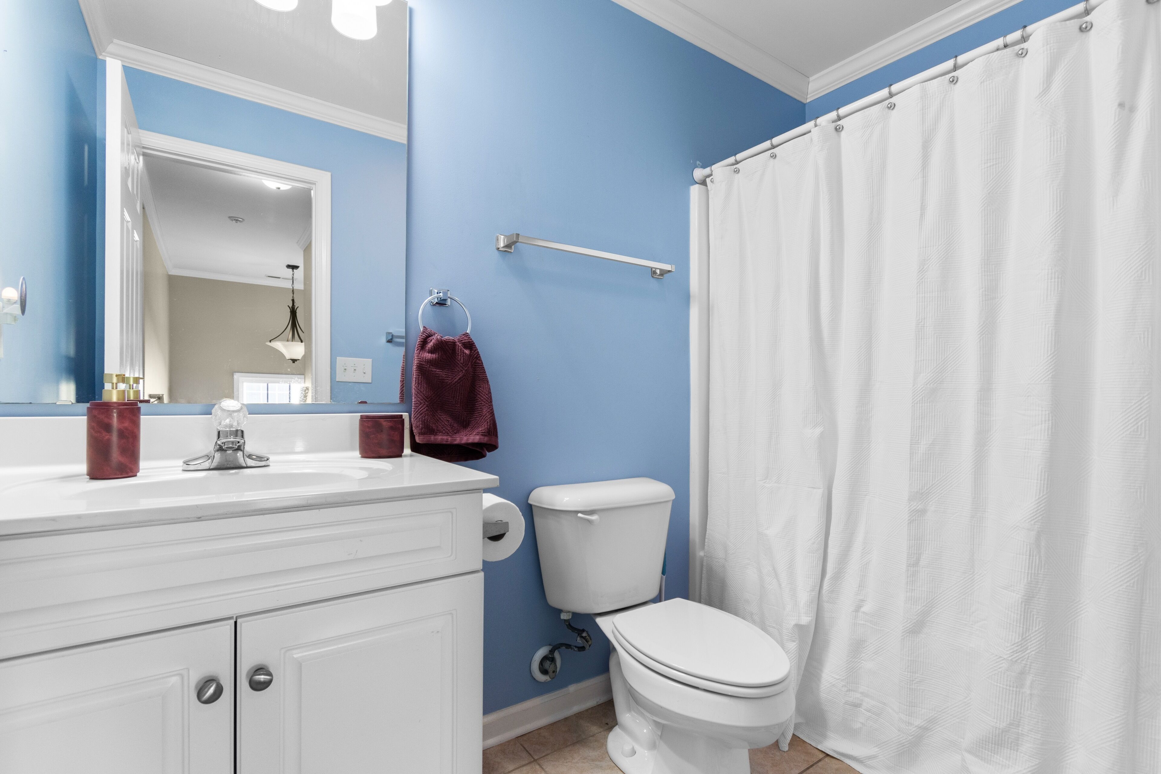 A bathroom with a white sink, toilet, and shower curtain.