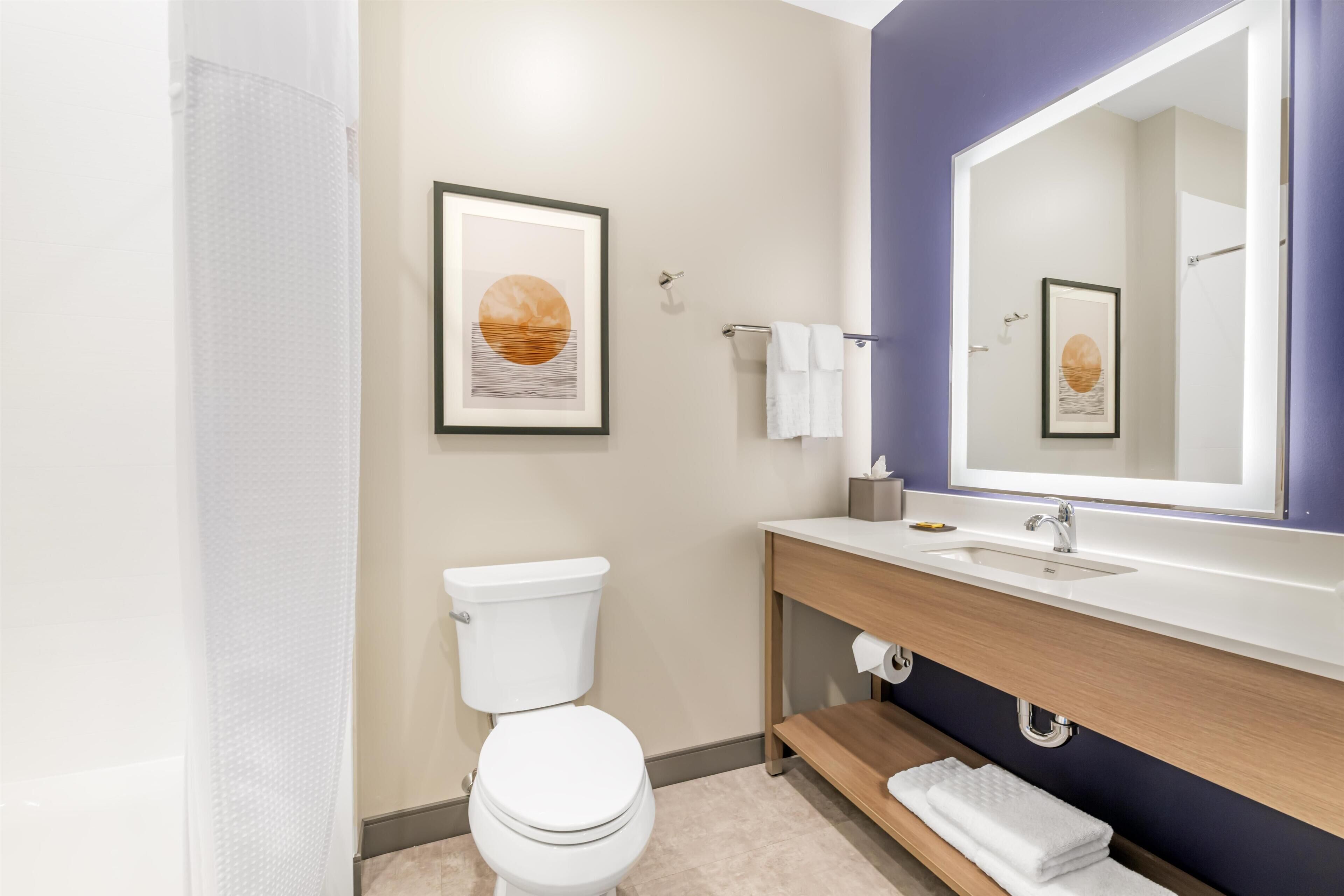 Un baño moderno con inodoro, lavabo y espejo.