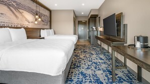 Habitación de hotel con una cama grande, un escritorio y un televisor de pantalla plana, además de un televisor montado en la pared y un cartel.
