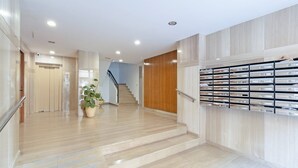 Eine moderne Hotelhalle mit einer Holztreppe, einer Pflanze und einem an der Wand befestigten Stauraum.