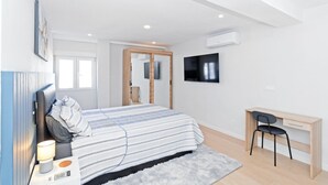 Ein modernes Schlafzimmer mit Bett, Nachttisch, Lampe und Schreibtisch mit Stuhl.