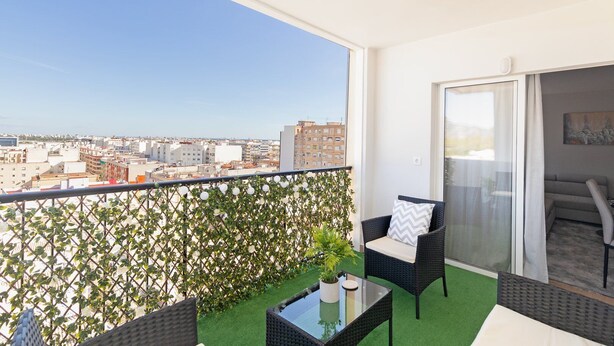 Ein Balkon mit Blick auf die Stadt, eine Glastür und eine Sitzecke mit Tisch und Stühlen.