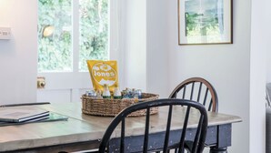 Ein Essbereich mit Tisch, Stühlen, einer Snack-Korb und einem Fenster mit Grünpflanzen vor der Aussicht.