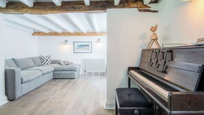 Ein Wohnzimmer mit Ecksofa, Klavier und Heizkörper.