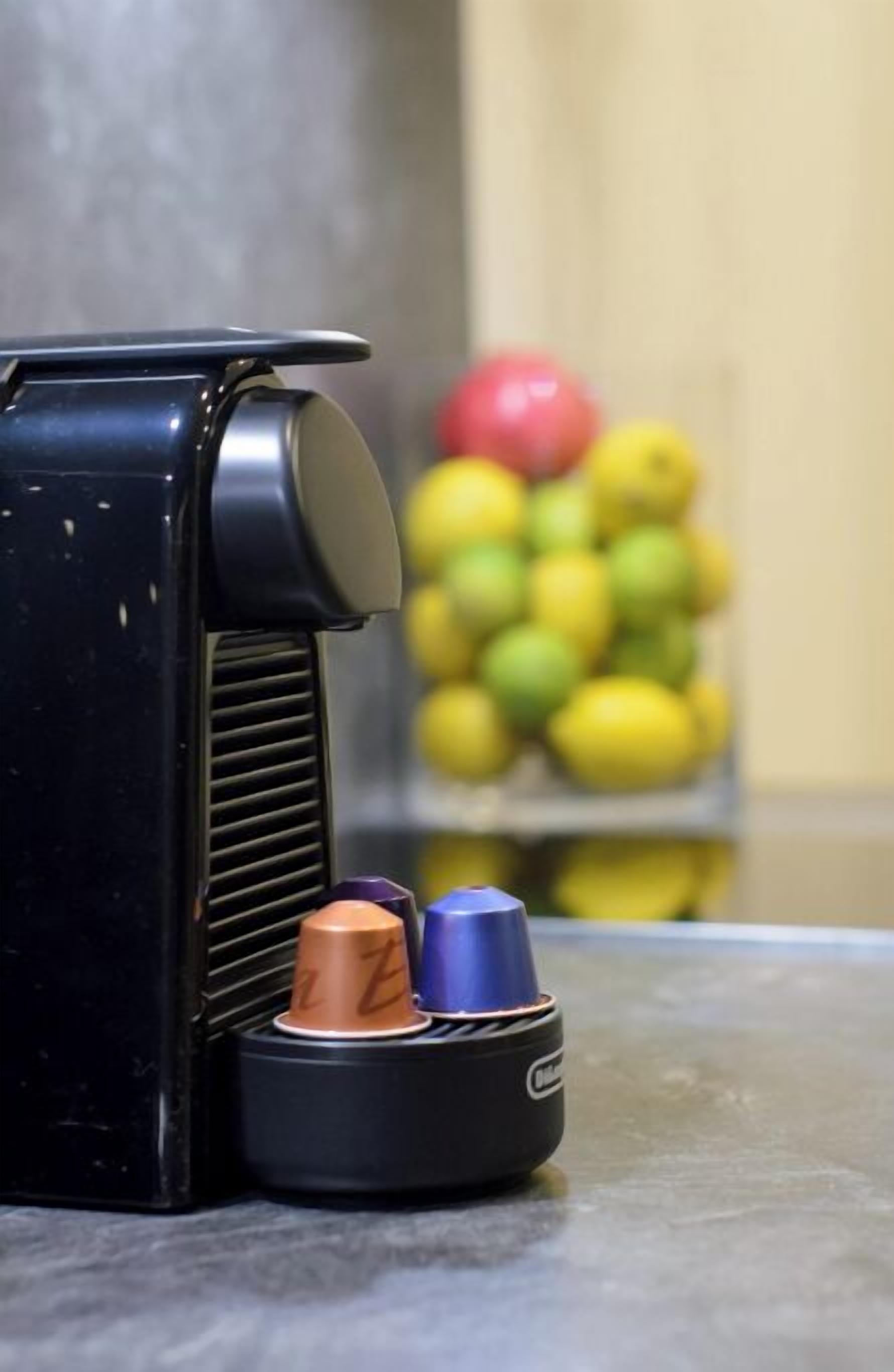 A black coffee machine with a drip tray and a stack of colorful cups.