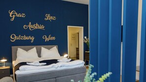Une chambre moderne avec un grand lit, des tables de chevet et un mur orné d’un texte.