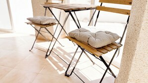 Twee opklapbare stoelen met kussens, een houten tafel en een gestructureerde muur.