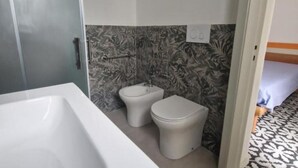 Un baño con bañera, inodoro y bidé.