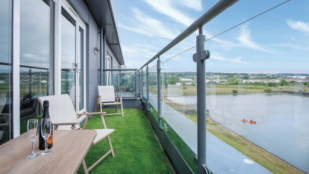 A balcony with a table, two chairs, and a bottle of champagne. - Skyline Duplex Penthouse - Llanelli (Llanelli)