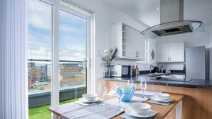 A modern kitchen with a dining area, large windows, and a view of the city. - Skyline Duplex Penthouse - Llanelli (Llanelli)