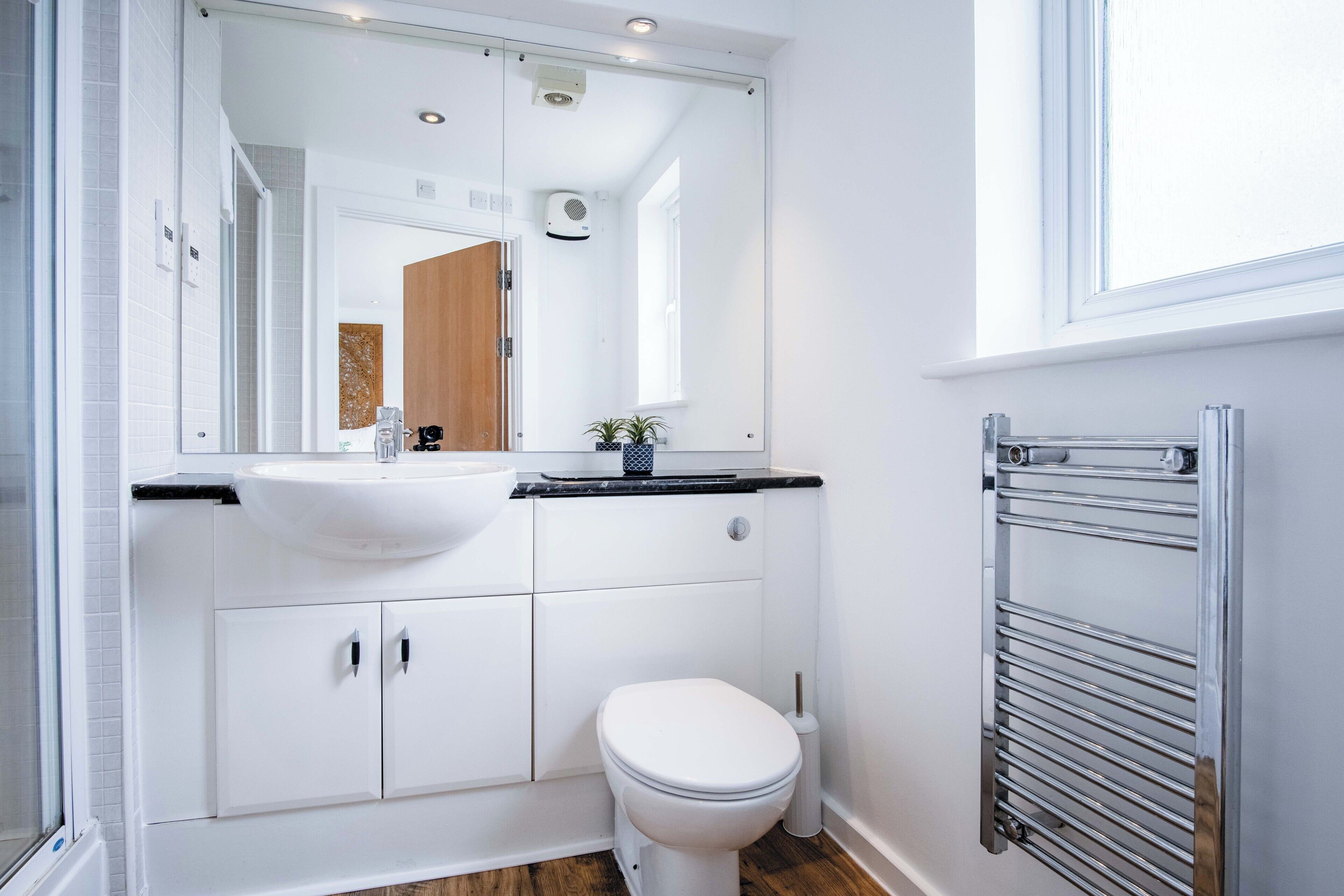 Un bany modern amb un lavabo blanc, un vàter i un mirall sobre el lavabo.