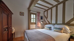 Une chambre à coucher avec un grand lit, une armoire en bois et une fenêtre avec des rideaux.