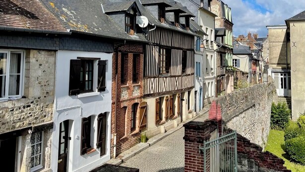 Une ruelle étroite pavée, bordée de b âtiments historiques, où l’on trouve un mélange de constructions en pierre et à ossature bois.