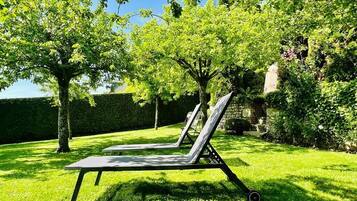 A garden with a sun lounger and a stone wall.